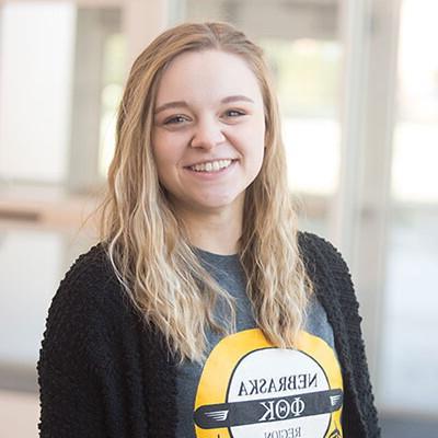 Young woman smiling standing in front of glass doors.